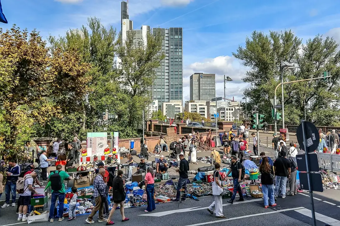 Händler und Besucher auf dem Flohmarkt am Schaumainkai, im Hintergrund die Frankfurter Skyline