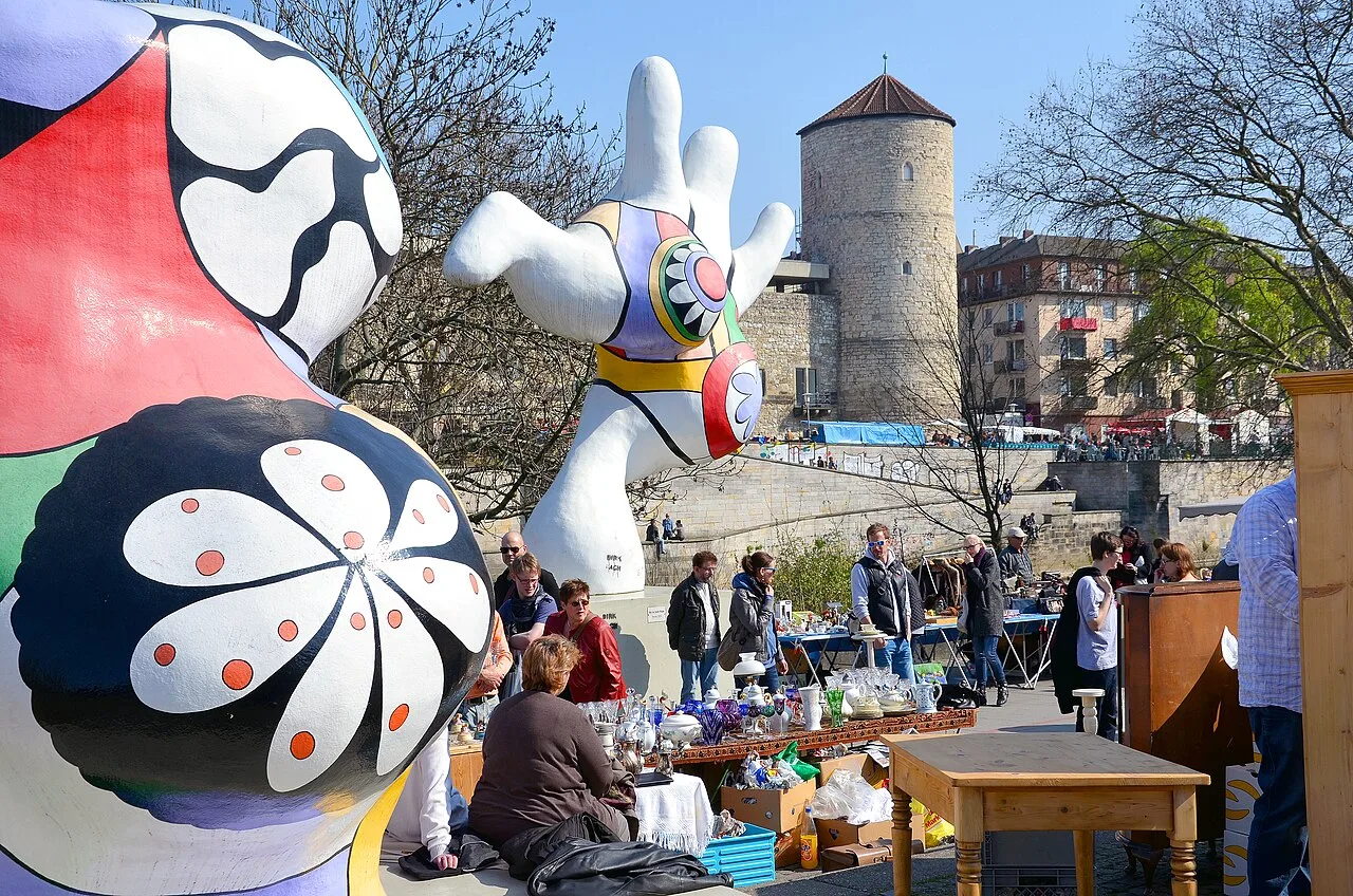 Verkaufsstände des Altstadtflohmarkts zwischen den Nana-Skulpturen am Leibnizufer, im Hintergrund der Beginenturm