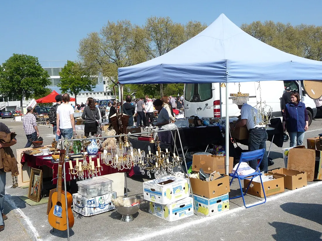 Stand mit Kronleuchtern, Geschirr und Kisten auf dem Asphalt des Mannheimer Krempelmarkts